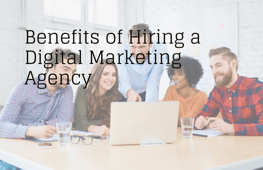 A diverse team of professionals collaborating around a laptop in a bright office, representing the benefits of hiring a digital marketing agency.
